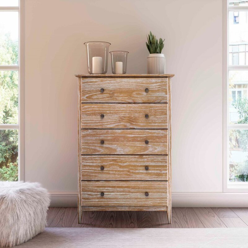 A wood dresser against a wall with candles and a potted plant on top.